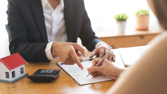 Deux personnes signent un contrat pour une maison.