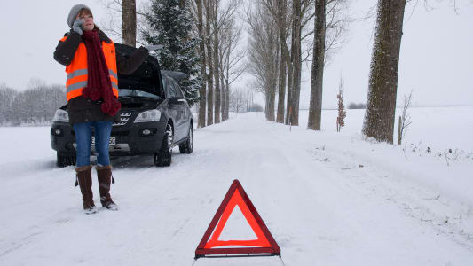 Une femme au t�l�phone, alors que sa voiture est en panne, sous la neige.