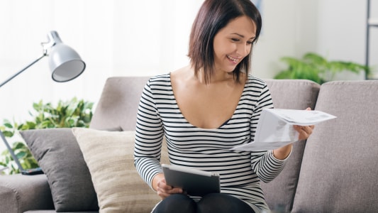 Une femme regardant un document et une tablette.