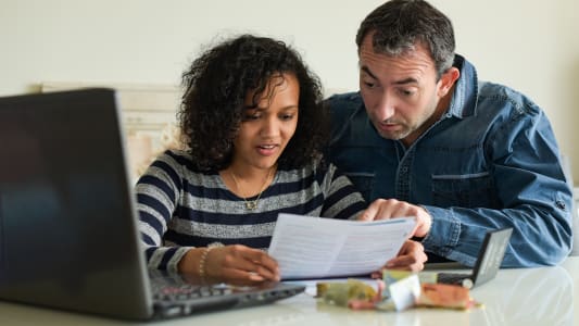 Un couple regardant des factures devant son ordinateur.