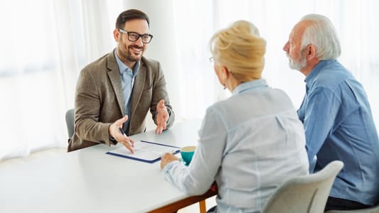 Homme discute avec couple �g� autour d'une table.