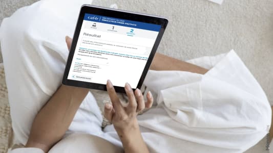 Personne utilisant une tablette pour naviguer sur un site web. Prime d'activit� CAF