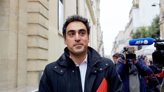 Homme avec dossier rouge interview&eacute; par des journalistes en ext&eacute;rieur.
