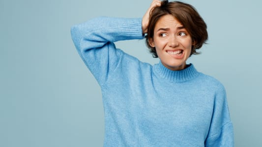 Jeune femme caucasienne triste portant un pull tricot� disant oups isol�e sur un fond de studio bleu clair pastel uni.