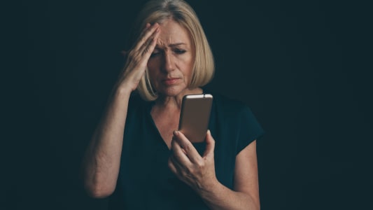 Une femme tenant un t�l�phone avec un visage triste.