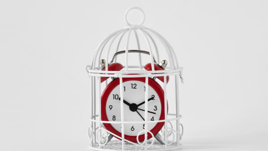 Un r�veil rouge dans une cage sur fond blanc.