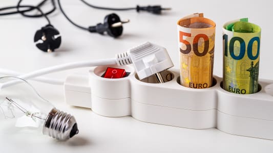 Un billet de cinquante et cent euros sur une prise de courant, avec une ampoule.