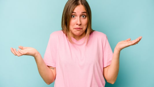 Jeune femme isol�e sur fond bleu, doutant et haussant les �paules dans un geste interrogateur.