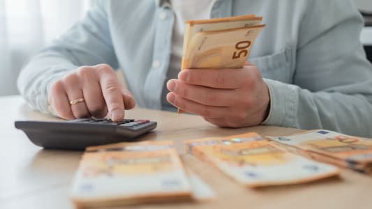Un homme avec de l'argent et une calculatrice remplissant des papiers.