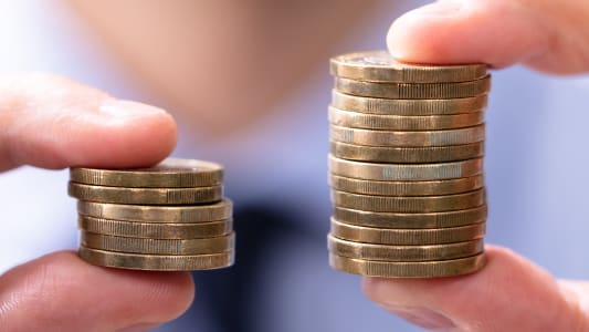 Un homme comparant deux piles de pi&egrave;ces.