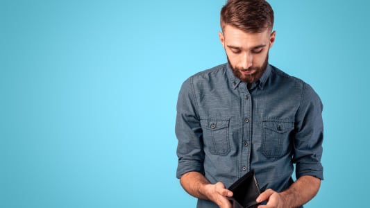 Concept de pauvret&eacute; et de ch&ocirc;mage. Jeune homme d&eacute;sesp&eacute;r&eacute; montrant un portefeuille vide sans argent sur fond de studio bleu. Jeune de la g&eacute;n&eacute;ration Y perdant son emploi ou son entreprise pendant la crise &eacute;conomique.