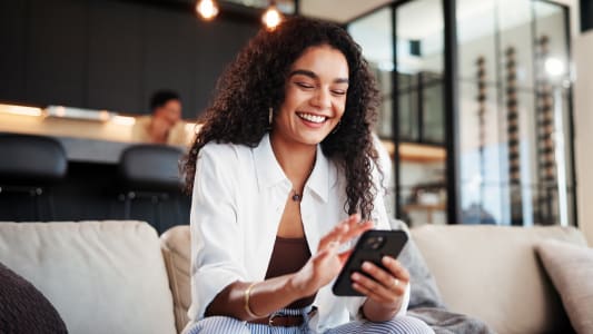 T&eacute;l&eacute;phone portable, sourire, femme sur le canap&eacute; &agrave; la maison