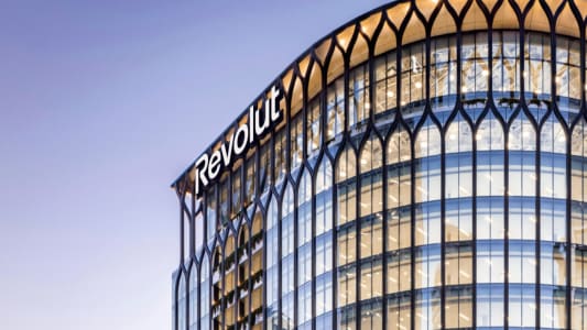 Immeuble moderne en verre avec logo Revolut illumin&eacute;.