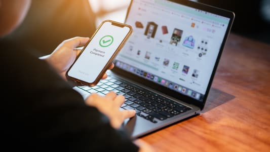 Une personne utilise un smartphone pour payer ses achats en ligne sur un site web.