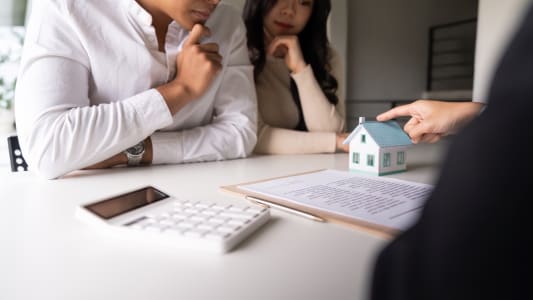 Un couple consulte un agent immobilier pour acheter une maison.