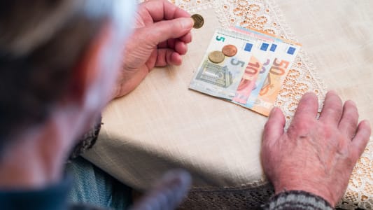 Personne &acirc;g&eacute;e compte des billets et pi&egrave;ces en euros.
