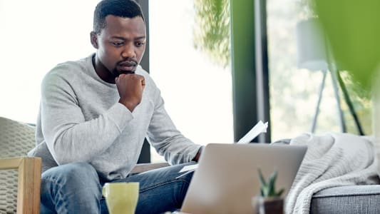 Un homme inquiet en regardant des documents et son ordinateur.