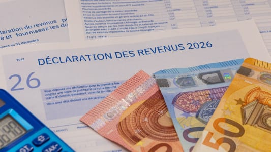Déclaration d?impôts, billets en euros et calculatrice bleue.