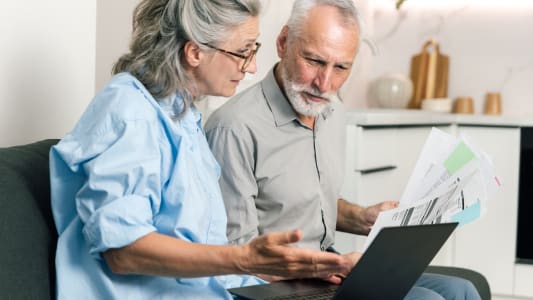 Un couple discute des factures et du budget tout en examinant les relev&eacute;s sur un ordinateur portable.