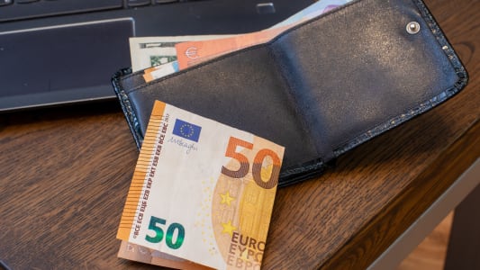 Portefeuille en cuir noir avec un billet de 50 euros sur un bureau en bois &agrave; c&ocirc;t&eacute; d'un ordinateur portable. Finance, budget personnel, paiement en ligne. Photo r&eacute;elle