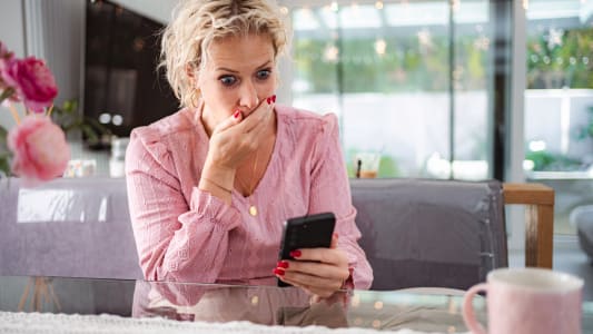 Femme ressentant le choc et les mauvaises nouvelles sur son smartphone &agrave; la maison