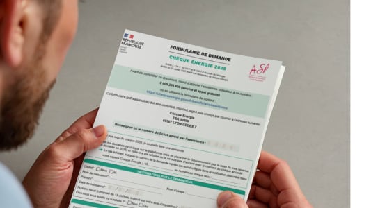 Un homme tient un formulaire de demande de ch&egrave;que &eacute;nergie.