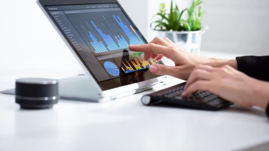 Femme d'affaires analysant un graphique sur un ordinateur portable au travail