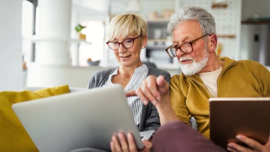 Un couple de personnes &acirc;g&eacute;es regarde un ordinateur.