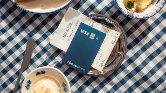 Carte bancaire et addition sur une table &agrave; carreaux bleus.