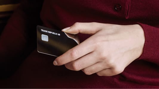 Main tenant une carte bancaire noire Trade Republic.