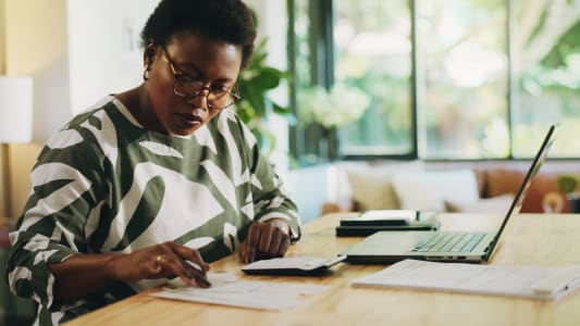 Finance, budg&eacute;tisation et femme noire avec facture &agrave; domicile pour la planification financi&egrave;re, les &eacute;conomies ou l'audit. Richesse, personne ou ordinateur portable avec documents de re&ccedil;u pour le retour d'imp&ocirc;t, examen de compte ou gestion d'actifs.