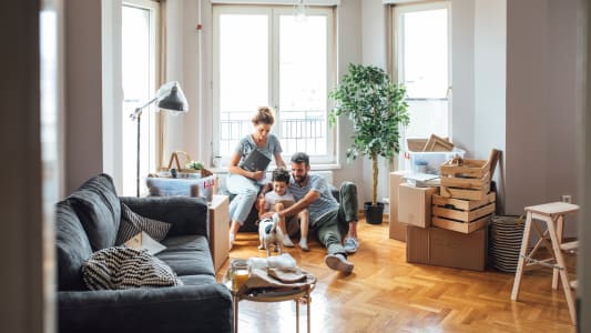 Famille dans un salon entour&eacute;e de cartons de d&eacute;m&eacute;nagement.