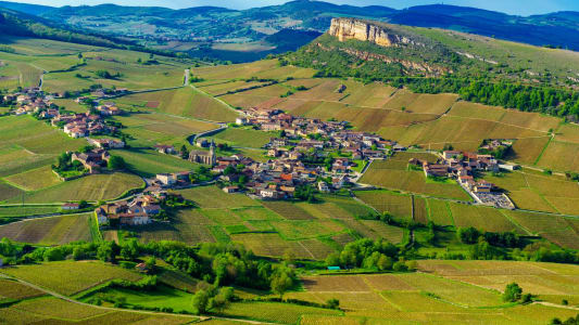Village entouré de vignobles et collines verdoyantes sous le soleil. Pouilly Solutre