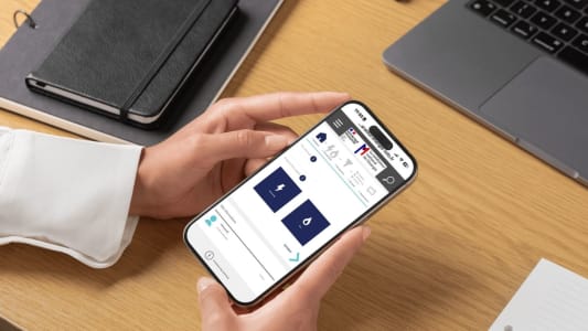 Une main tenant un smartphone affichant le comparateur du médiateur de l'énergie
