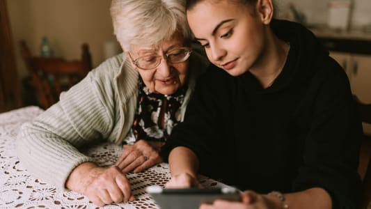 La grand-mère caucasienne âgée et sa belle petite-fille adolescente regardent les photos sur la tablette dans la pièce.