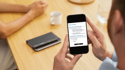 Homme consultant des options sur un smartphone, table en bois. impots