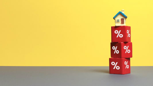 Maison posée sur des cubes rouges avec des pourcentages blancs.