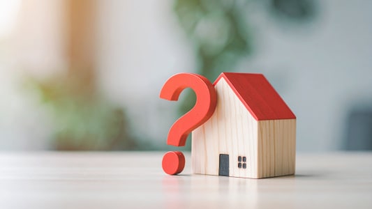 Maison en bois avec un point d?interrogation rouge.