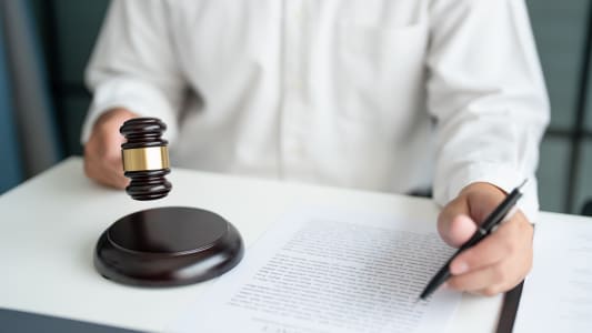Une personne tient un maillet devant un document avec un crayon &agrave; la main. Concept de la justice.