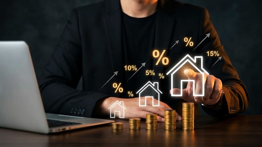 Homme en costume, pièces, maisons, pourcentages, investissement immobilier, ordinateur.
