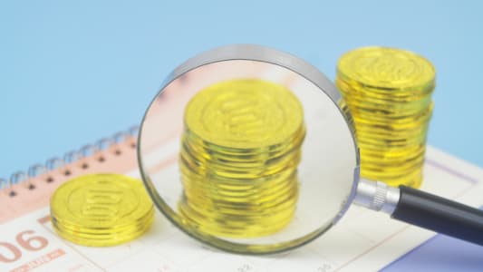 Loupe sur piÃces d?or posées sur un calendrier.
