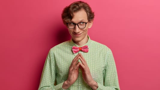 Coup isol&eacute; d'un homme rus&eacute; et r&eacute;fl&eacute;chi qui a un plan de g&eacute;nie mal&eacute;fique, il entrecroise les doigts avec l'intention de faire quelque chose, a une expression pens&eacute;e satisfaite, porte une &eacute;l&eacute;gante chemise verte et un n?ud papillon, se tient &agrave; l'int&eacute;rieur.