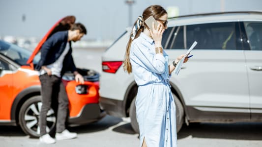 Une femme passant un appel apr&egrave;s un accident de voiture.