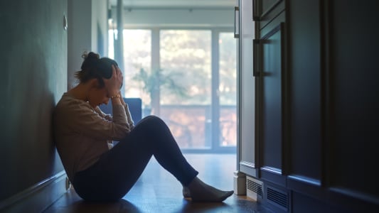 Une femme assise sur le sol dans le couloir de son appartement.