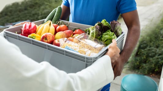 Livraison d'une caisse de légumes et de fruits.