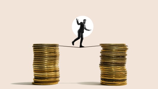 Un homme d'affaires marche d'une pile de pièces à une autre le long d'une corde raide.