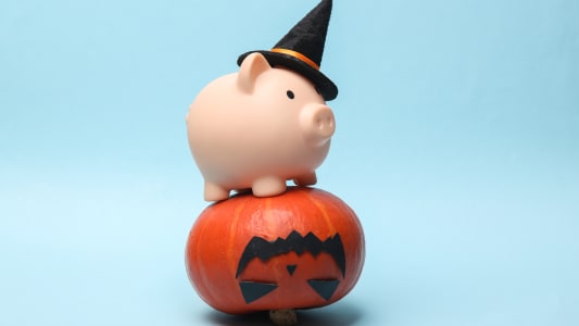 Citrouille d'Halloween avec une tirelire dans un chapeau de sorcière sur un fond bleu