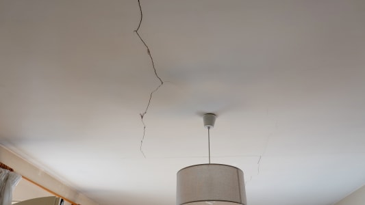 Une fissure visible au plafond au-dessus d'une lampe