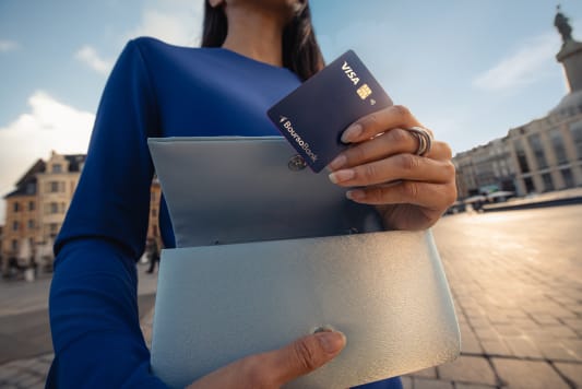 Femme tenant une carte bancaire Visa et un portefeuille.