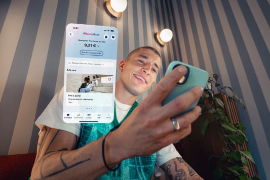 Homme souriant utilise une application bancaire sur son smartphone.